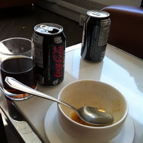 a bowl of soup and soda cans on a table