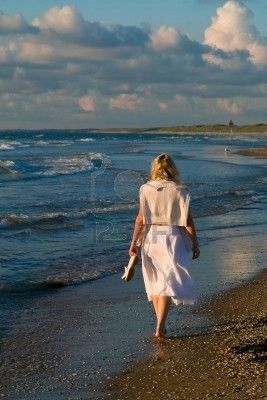 Mujer joven alejándose por la orilla del mar.