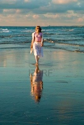 Mujer joven acercándose por la orilla del mar.