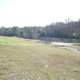 A typical closed landfill requires continuous maintenance. Here a sediment pond has been cleared but more work remains to improve drainage as indicated by the ponded water on the right. A typical closed landfill requires continuous maintenance. Here a sediment pond has been cleared but more work remains to improve drainage as indicated by the ponded water on the right.