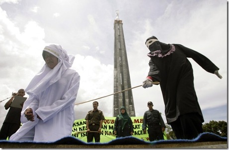 Murni Amris, an Acehnese woman, is caned as part of her sentence in the courtyard of a mosque in Aceh Besar district, Indonesia's Aceh province October 1, 2010