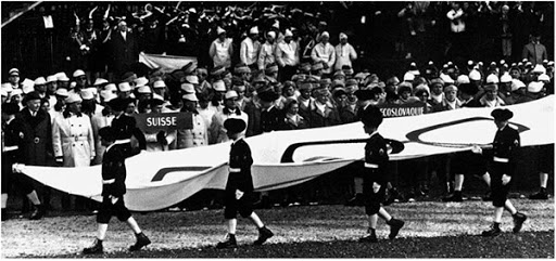 The alpine troops carry the Olympic flag.