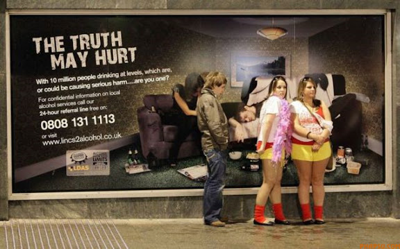 RNPS IMAGES OF THE YEAR 2009 - Revellers stand in front of a poster warning of alcohol abuse during a "Carnage" event,  in Lincoln, , eastern England April 27, 2009. "Carnage" was an organised, unofficial,  event involving university students in Lincoln visiting a number of bars on Monday night and into the early hours of Tuesday morning. Local police estimated that about 1200 people attended.   REUTERS/Darren Staples   (BRITAIN SOCIETY)