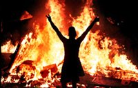 Rioter stands before bonfire