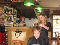 A Dutch client having her hair done by a travelling stylist in a village bar