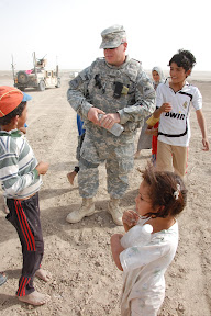 Chief Warrant Officer Fred McKiel from Horizon City, Texas, assigned to Task Force ?Pathfinder? 2nd Battalion, 29th Field Artillery Regiment, interacts with children in Iraq?s Muthanna province while checking on a hearing aid distribution project, Sept. 8. Photo by Maj. Myles B. Caggins III