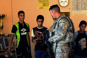 Sgt. Mark O. Harris, agriculture advisor team noncommissioned officer, 1st Battalion, 77th Field Artillery Regiment and a Waynesboro, Va., native, shakes hands with Iraqi children during a visit to the Al-Hay Youth Center in Wasit Province Sept. 7. The visit was to meet with members of the youth center to view the improvements needed. (U.S. Army Photo by Pfc. Bethany L. Little)