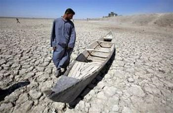 Akeed Abdullah stands next to his boat in a dried marsh in Hor al-Hammar in southern Iraq. (Photo by Gorillas Guides)