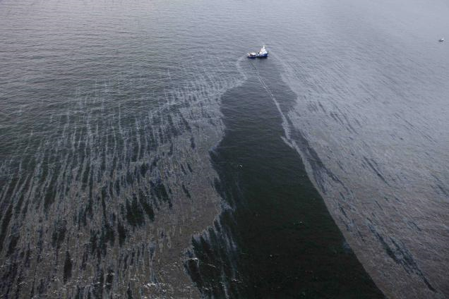 In the Gulf of Mexico, more than 50 miles southeast of Venice on Louisiana's tip, a boat with an oil boom tries to contain oil spilled from the explosion and collapse of the Deepwater Horizon oil rig. Photo: AP