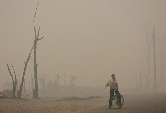 A man stops while riding a bike in the thick smoke in the village of Keltsy in Ryazan region, some 180 km (111 miles) southeast of Moscow, Wednesday, Aug. 4, 2010.  AP / Misha Japaridze
