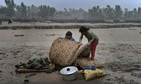 Children displaced by flooding in north-west Pakistan attempt to protect their belongings from renewed downpours. A Majeed / AFP / Getty Images