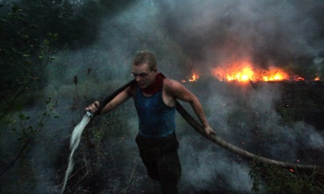 A Russian firefighter carries a firehose to the fire line. Photo: DPA via thelocal.de