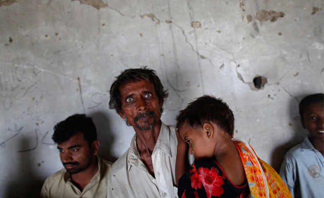A man holds his daughter as he and other flood victims find shelter from a storm in an abandoned building in Pakistan's Muzaffargarh district on September 4, 2010. REUTERS / Damir Sagolj