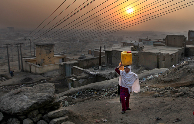 An Afghan girl carries water in a plastic container as she ascends a slope on the way towards her house in Kabul, Afghanistan, Monday, Dec. 27, 2010. AP Photo / Altaf Qadri