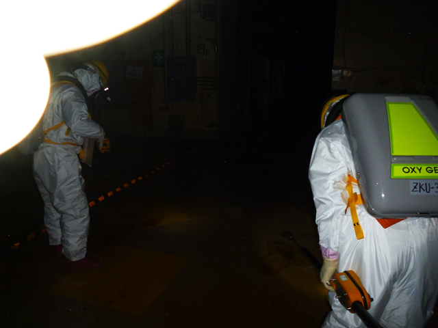Workers examine puddles on the first floor, inside the reactor building of Fukushima Daiichi Nuclear Power Station Unit 2, 18 May 2011. TEPCO