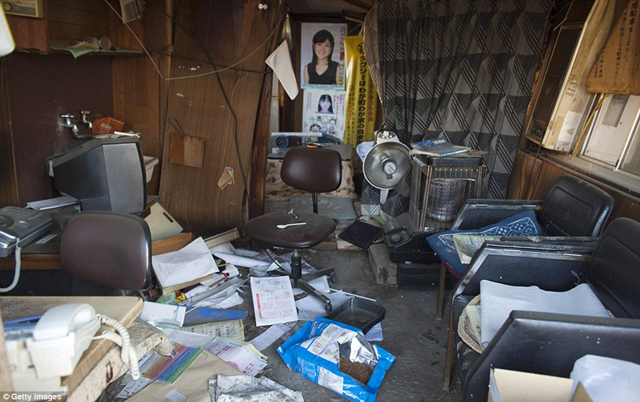 Domestic nightmare: Pictures still hang from the walls, but the rest of this house within the Fukushima exclusion zone has been reduced to rubble, 12 April 2011. Getty Images / dailymail.co.uk