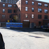 Haifa-Bint Kadi, Groundwork’s artist-in-residence, at the Cottage Gardens Housing Development, next to the most recent section of her Wave Wall mural, designed and painted by children from the site’s after-school program.