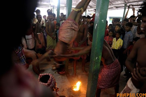 An Indian Hindu devotee (C) is swung by others as he hangs himself upside down over a fire during the ritual of Shiva Gajan at a village in Bainan, some 80 kms south of Kolkata, on April 14, 2010. Devotees believe that by enduring the pain, Shiva, the Hindu god of destruction, will grant their prayers. Thousands took part in the month-long festival which culminates with the worship of Shiva on the auspicious day of Chaitra Sankranti, the last day of the Bengali calendar year.    AFP PHOTO/Deshakalyan CHOWDHURY (Photo credit should read DESHAKALYAN CHOWDHURY/AFP/Getty Images)