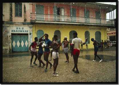 A group of teenagers play a game of soccer in the rainy streets of Cap Haitien.