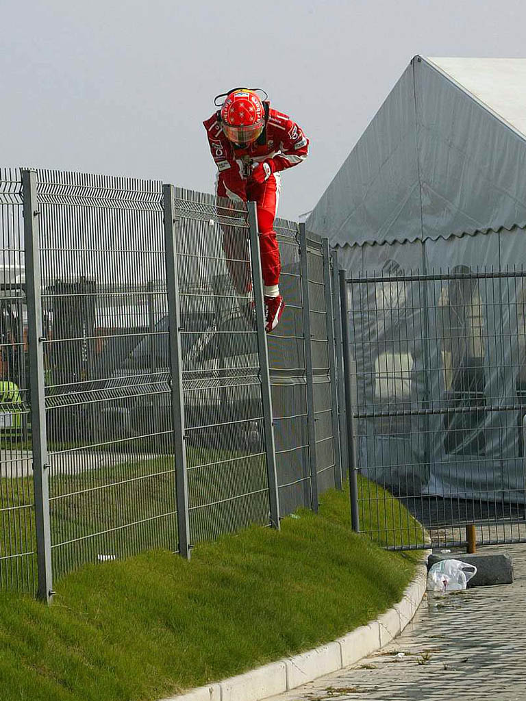Михаэль Шумахер перелезает через забор после вылета на Гран-при Китая 2005