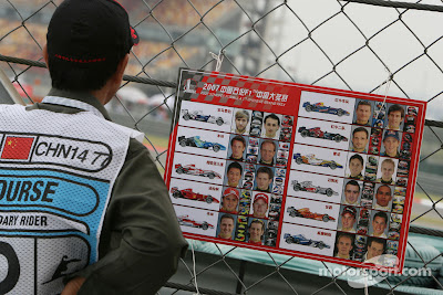 маршал на Гран-при Китая 2007 изучает фотографии гонщиков