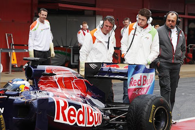механики Force India и Пол ди Реста наблюдают за задней частью болида Toro Rosso Даниэля Риккардо на предсезонных тестах 2011 в Барселоне