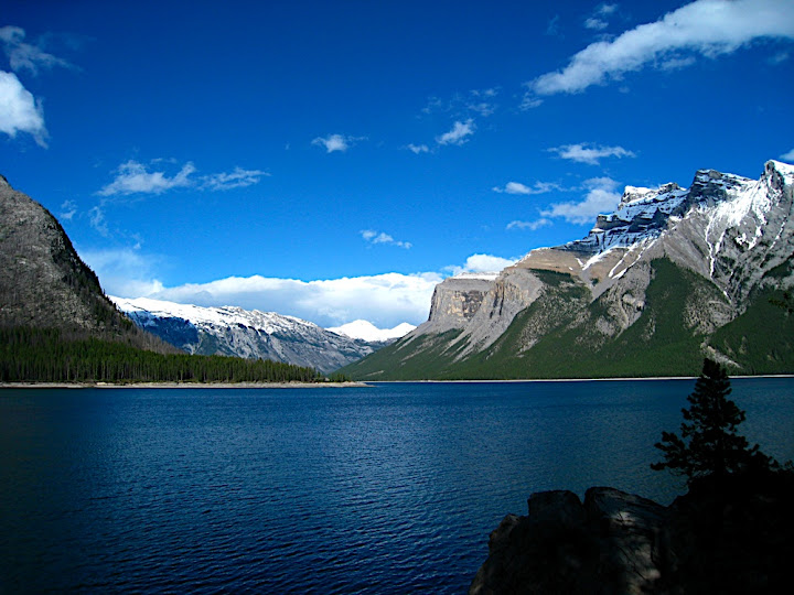 Blue water, little fluffy clouds and big rock