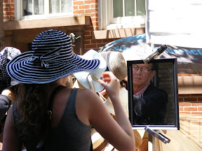 Lady trying on a hat at streetside stall.