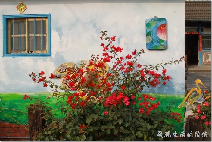 台南-土溝村(竹仔腳)。「幾米」裝置藝術的隔壁有住家，這間「白毛伯」的家牆壁上有彩繪，還掛了一塊畫著「平安」兩字的覘板。九重葛後面還有一隻蝸牛爬在樹葉上，象徵「安居樂業」。