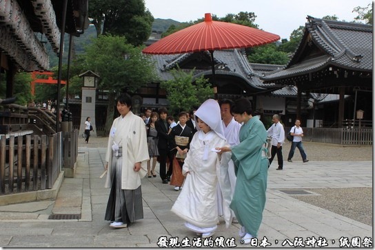 八坂神社-紙園祭，新人的前面有兩位前導，還有人為新娘特別撐傘，後面還跟著家屬及賓客，其實旁邊還有穿西裝的人員維持秩序，排除擋道的遊客。 