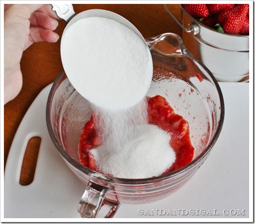 adding sugar to strawberry jam, making strawberry jam, silver measuring cup