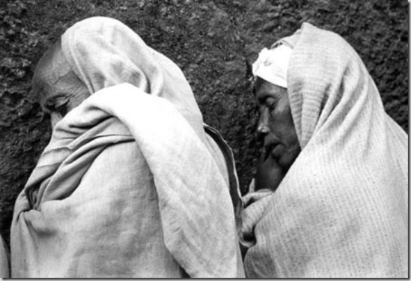 Pilgrims wrapped in theirs netelas (ceremony cloth) praying outside during a religious worship in Bet Madhane Alem church. . Ethiopian Orthodox Coptic have a deep faith  with their roots sank in the early Christians and with Judaism influences