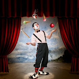 Clown performing on stage with red curtains