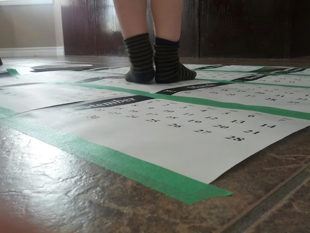 Close up of preschool child standing on a calendar hop game