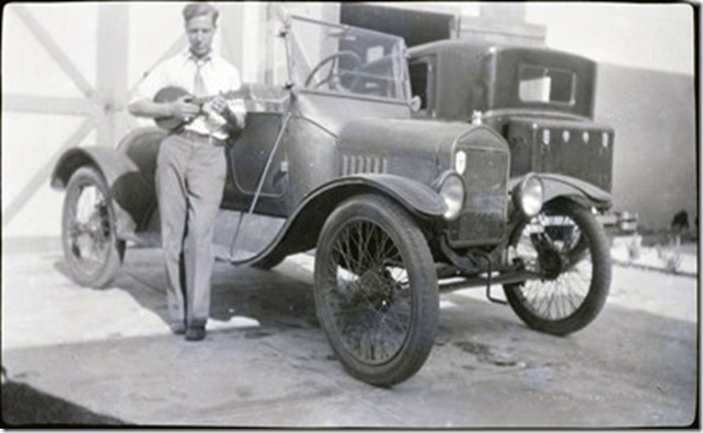 Arthur Iverson holding a mandolin standing in front of an automobile