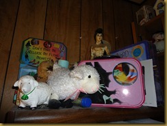 This is the top shelf of the bookcase that is next to the computer.  The bookcase is filled with teacher resources and one shelf of crochet books/patterns.  The doll was brought back from Vietnam by my father in 1971.  I just started collecting sheep.  Behind the sheep are more Wiz of Oz figurines.  The other lunch box, which I have used.  The wiz of Oz board game, and tucked in front is a piece of art I won from a blog.  I don;t have a spot for it yet.