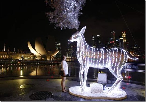 a-tourist-looks-at-a-reindeer-display-lit-up-in-preparation-for-christmas-celebrations-in-front-of-the-skyline-of-the-finan599x0