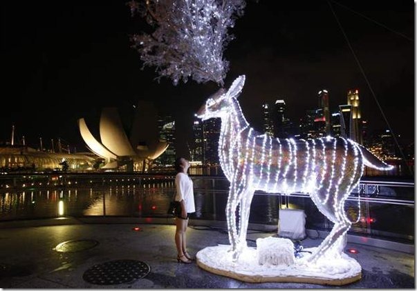 a-tourist-looks-at-a-reindeer-display-lit-up-in-preparation-for-christmas-celebrations-in-front-of-the-skyline-of-the-finan599x0 a-tourist-looks-at-a-reindeer-display-lit-up-in-preparation-for-christmas-celebrations-in-front-of-the-skyline-of-the-finan599x0
