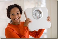 Happy Black woman holding scale