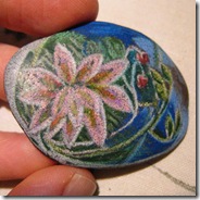 smooth beach rock with a white water lily and silver decoration