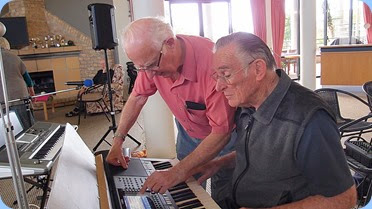 Peter Jackson helps Roy Steen set-up the Yamaha keyboard before Roy played for the audience. Photo courtesy of Dennis Lyons
