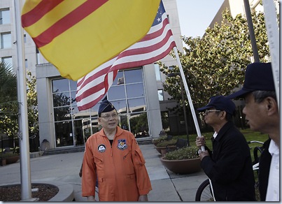 San Jose "freedom fighter'',  Ly Tong, 63, wears his orange flight suit before entering court at the Santa Clara County Hall of Justice in San Jose, Calif. on Wednesday, May 23, 2012. His supporters, Phong Huynh and Tai Tran hold flags. The former Vietnamese Air Force officer and self-proclaimed "freedom fighter" is in court today to attend closing arguments in his trial for allegedly assaulting a Vietnamese singer with pepper-spray during a concert.  (Gary Reyes/ Staff) <br /><br />
