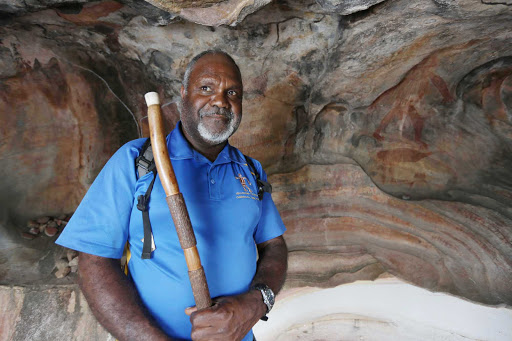 An aboriginal elder stands in front of a Bama Way cave painting during a G Adventures expedition in Queensland, northeastern Australia.