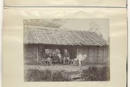 Nederlandse militairen zittend voor een houten huis in Nederlands-Indië, één leest een Bredase ('Bredasche') krant