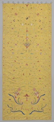 Gordijn, geel, geborduurd met vazen, bloemranken, hoorns van overvloed, pauwen en vlinders.