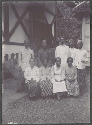 Groepsportret van mannen en vrouwen voor een gebouw, vermoedelijk op het terrein van een ziekenhuis in Nederlands-Indië