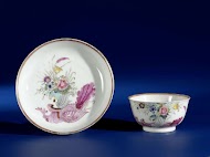 Bell-shaped cup and saucer with a snailornament and flowering plants