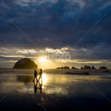 Silhouette of people walking on Oregon beach at sunset. by Gale Perry -  