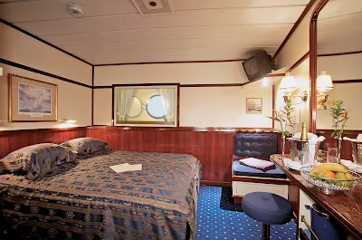 The Owner's Suite aboard Star Clipper and Star Flyer offers   guests a spacious bedroom with a small television, vanity area and king-size bed.