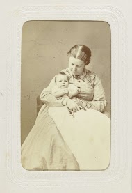 Studioportret van een vrouw met een baby in witte jurk op schoot